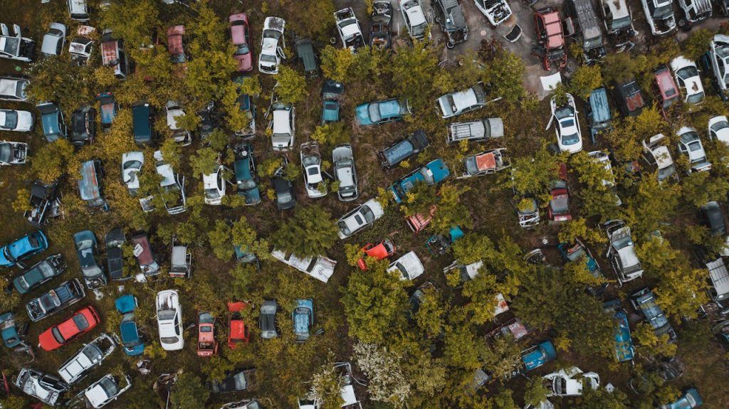 pexels-photo-4320472 Aerial top view of numerous abandoned rusted vehicles parked in chaotic order in green automobile graveyard in suburban district